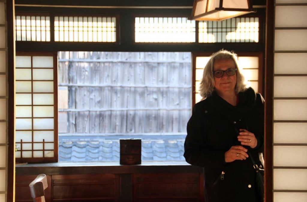 Jane King Hession stands in front of a window with Japanese screens